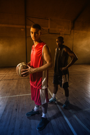 Portrait of two basketball players posing on gymの写真素材
