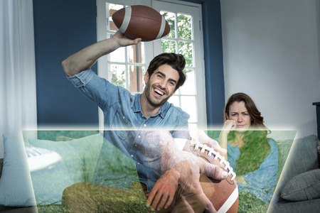 Composite image of man is watching american football match next to his bored wife at homeの写真素材