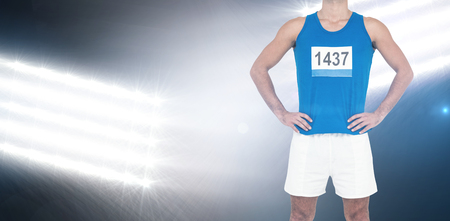 Male athlete standing on white background against spotlightsの写真素材