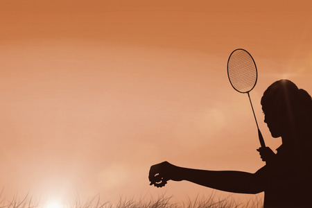 Female athlete holding a badminton racquet ready to serve  against sun risingの写真素材
