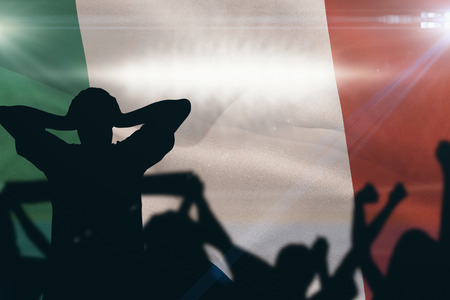 Silhouettes of football supporters against digitally generated image of blue tennis court  illuminate by spotlightの写真素材