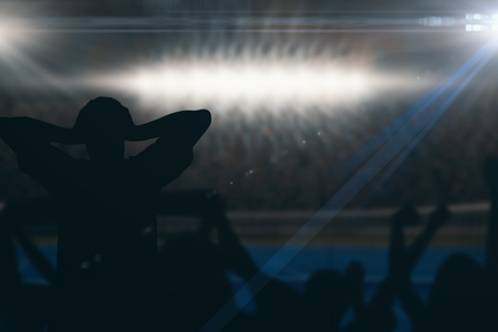 Silhouettes of football supporters against digitally generated image of blue tennis court  illuminate by spotlightの写真素材