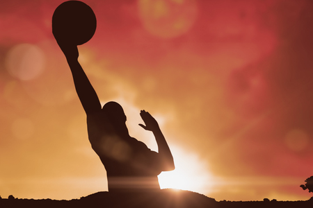 Sportsman playing a volleyball against landscape with sunsetの写真素材