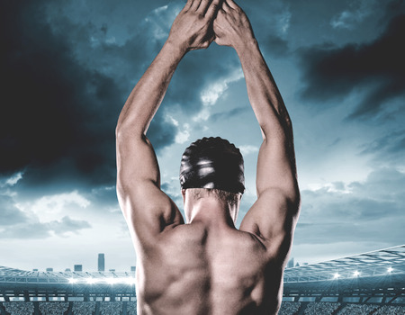 Swimmer preparing to dive against composite image of stadium with cloudy skyの写真素材
