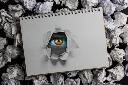 Bright orange eyes on female face against view of a notebookの写真素材