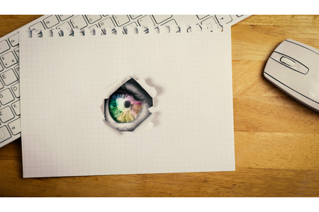 Multi colored eye on grey face against view of a notebook