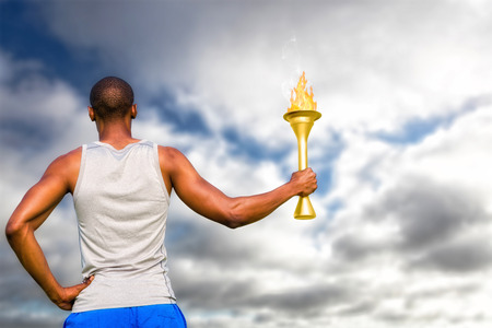 Rear view of sportsman holding a cup  against blue sky with cloudsの写真素材