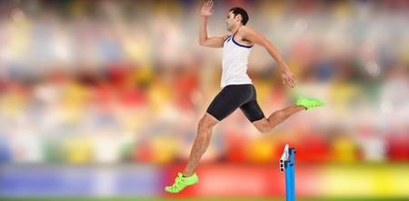 Male athlete running on track and jumping obstaclesの写真素材