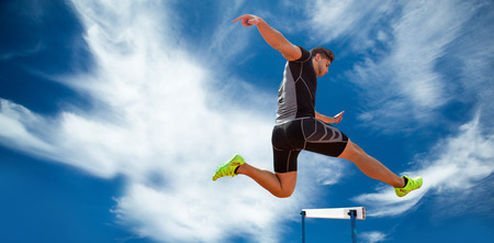 Athletic woman practicing show jumping against blue sky with clouds