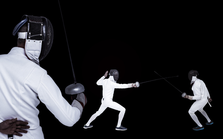 Man wearing fencing suit practicing with sword against black backgroundの写真素材