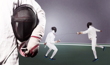 Mid-section of man standing with fencing mask against digitally generated image of bicolored backgroundの写真素材