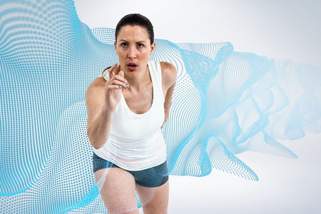 Energetic female athlete running against grey background