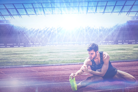Portrait of sportsman stretching his muscle  against race trackの写真素材