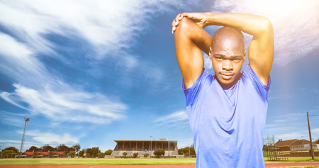 Athletic man stretching his arms against view of running track