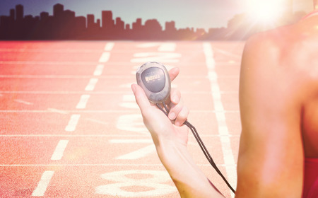Close up on a sportswoman holding a timer against composite image of race trackの写真素材