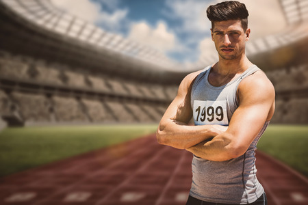 Portrait of handsome sportsman is posing with crossed arms  against view of a running trackの写真素材