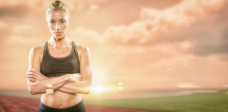 Athlete posing with arms crossed against composite image of race track in front of the oceanの写真素材