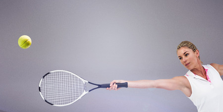 Athlete playing tennis with a racket  against grey backgroundの写真素材