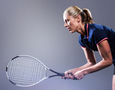 Tennis player playing tennis with a racket  against grey vignetteの写真素材