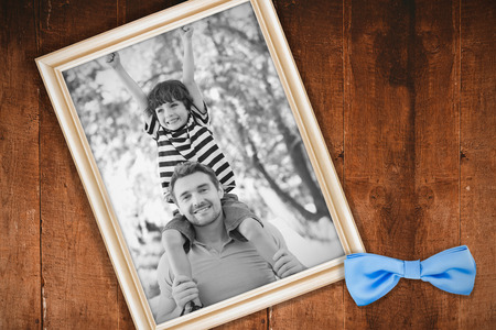 Father carrying a happy son on shoulders at park against white background with vignetteの写真素材