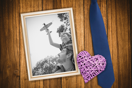 Boy with toy aeroplane sitting on fathers shoulders against wooden backgroundの写真素材