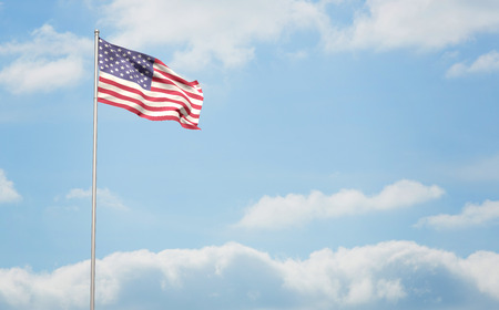 American flag waving on pole against cloudy sky background