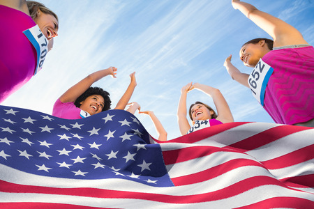 Digitally generated american flag rippling against five cheering runners supporting breast cancer marathonの写真素材