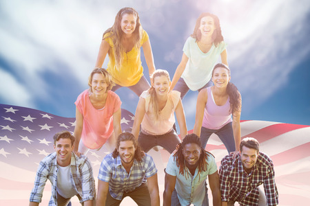 Happy friends making human pyramid against view of a blue skyの写真素材