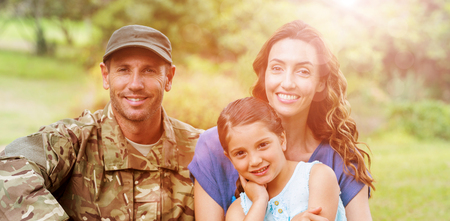 Portrait of smiling army man with family while sitting in parkの写真素材