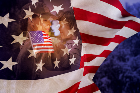 Army woman carrying son against focus on usa flagの写真素材