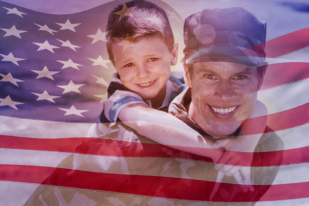 Digitally generated american flag rippling against happy soldier giving piggyback to his sonの写真素材