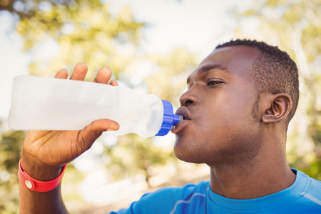Athletic man drinking water in a park