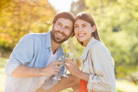 Portrait of couple holding glass of wine in parkの写真素材