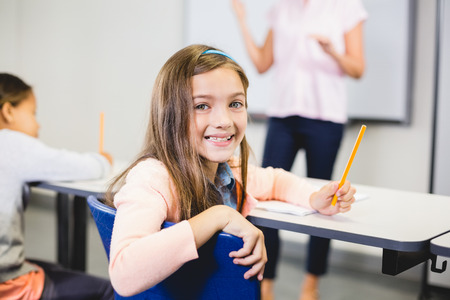 Portrait of schoolgirl smiling in classroom at school