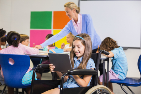 Disabled schoolgirl using digital tablet in classroom at schoolの写真素材