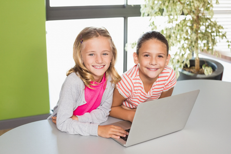 Portrait of kids using laptop in library at schoolの写真素材