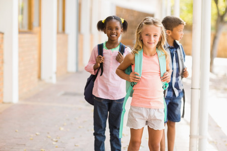 Smiling school kids standing in school corridor