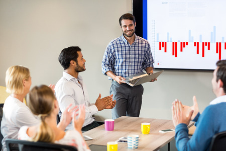 Coworkers applauding a colleague after presentation in the conference room