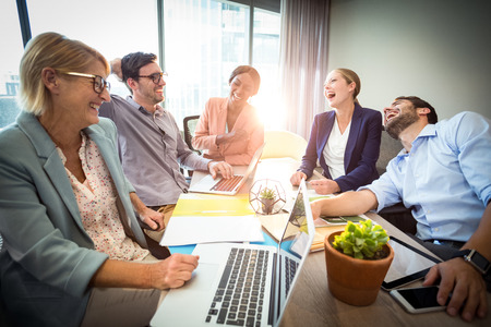Business people laughing during a meeting in the officeの写真素材