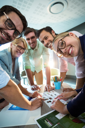 Close-Up of business people discussing over photograph during a meeting in the officeの写真素材