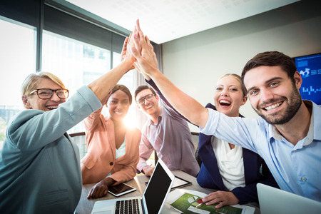 Portrait of business people giving high five at desk in the officeの写真素材