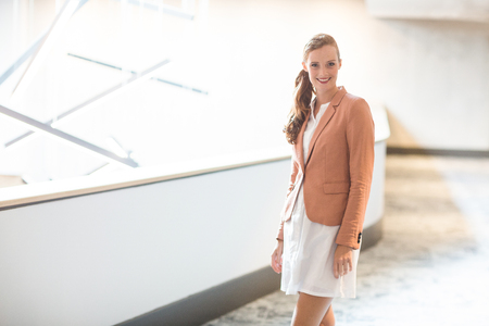 Portrait of beautiful young businesswoman standing in office corridorの写真素材