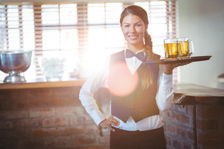 Waitress holding beers in a restaurantの写真素材