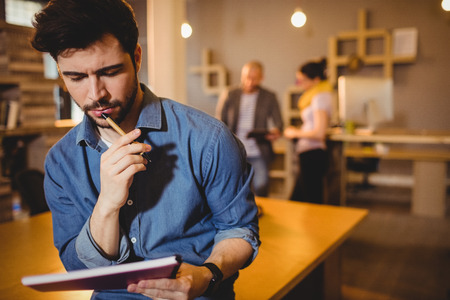 Graphic designer reading notes from his diary in office
