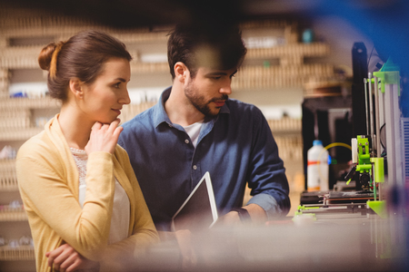 Graphic designers holding digital tablet looking at a model in office
