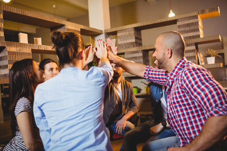 Colleagues giving high five during meeting at officeの写真素材
