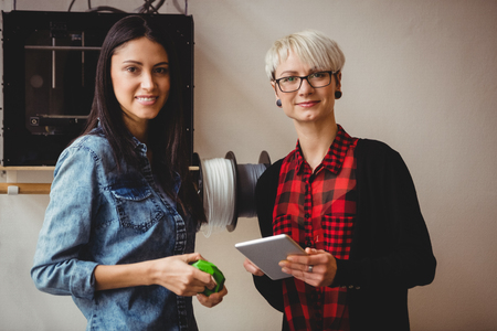 Portrait of female graphic designers holding digital tablet at office