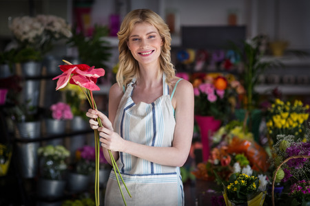 Portrait of smiling female florist holding flowers in the shopの写真素材