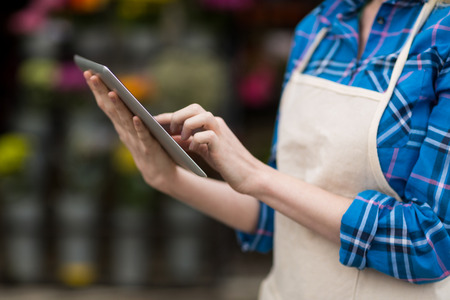 Mid-section of female florist using digital tablet in flower shop