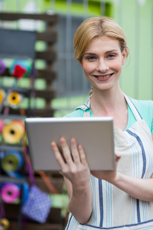 Portrait of happy female florist using digital tablet in flower shopの写真素材